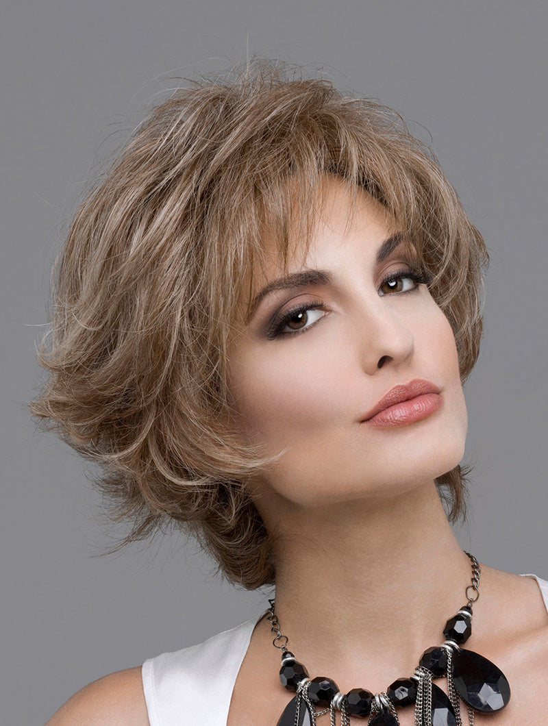 headshot of model wearing light brown spiky style wig