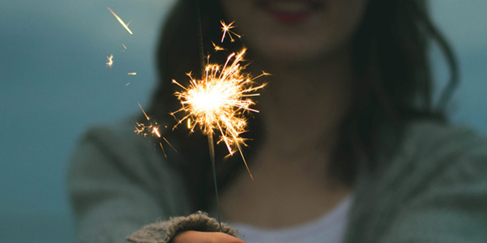 close up of a woman holding a lit sparkler