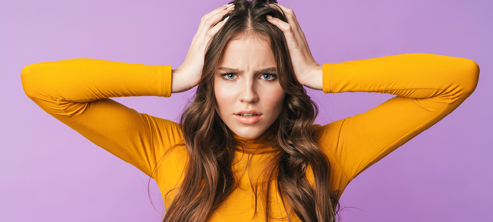 Woman with long, brown hair holds her head in confusion