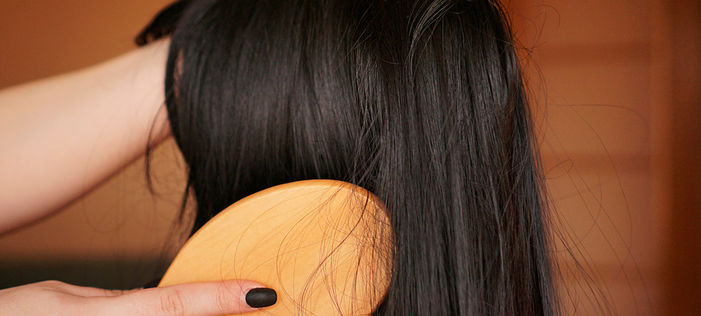 close up of a hand brushing out a dark brown wig