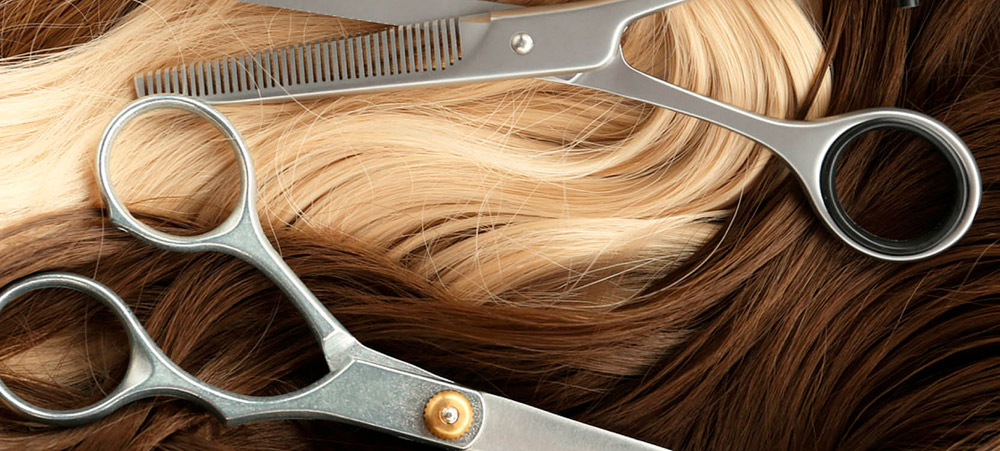 close up of hanks of blonde and brown hair with barber’s sheers laying on top of them