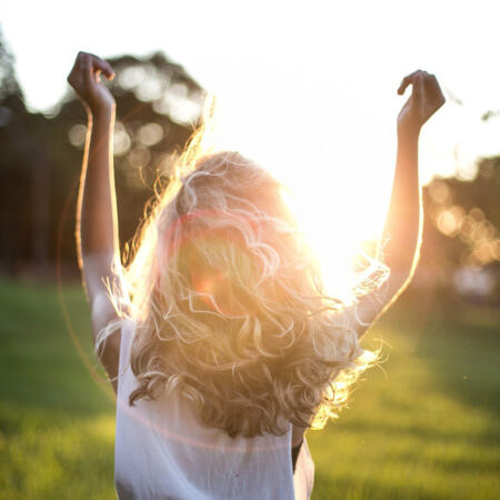 back of woman with blonde curly hair in the sunset
