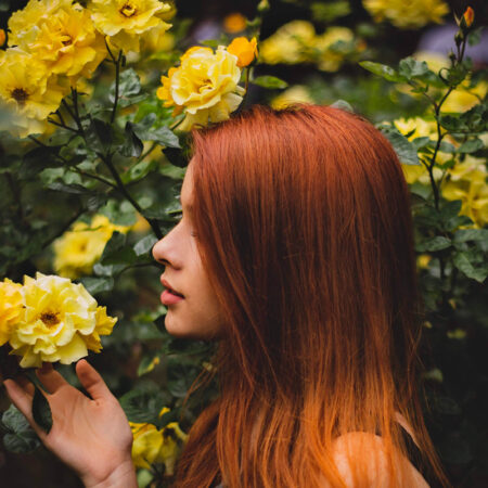 woman with red hair smelling yellow flower