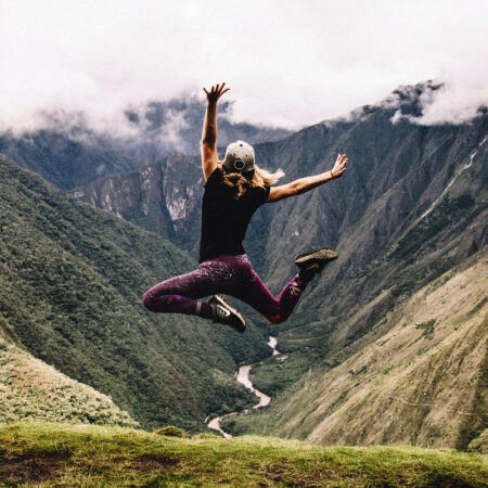woman with mountain range background leaping in the air